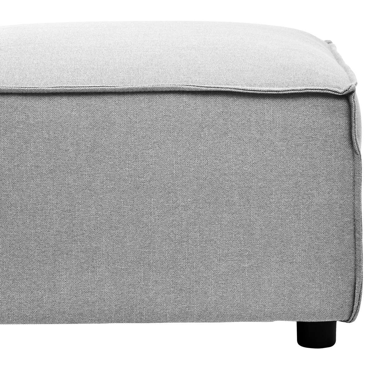 Grey fabric modular ottoman with a textured surface and a clean, modern design. The ottoman features a slightly rounded edge and rests on small black legs, providing a contemporary look suitable for various home decor styles