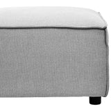 Grey fabric modular ottoman with a textured surface and a clean, modern design. The ottoman features a slightly rounded edge and rests on small black legs, providing a contemporary look suitable for various home decor styles