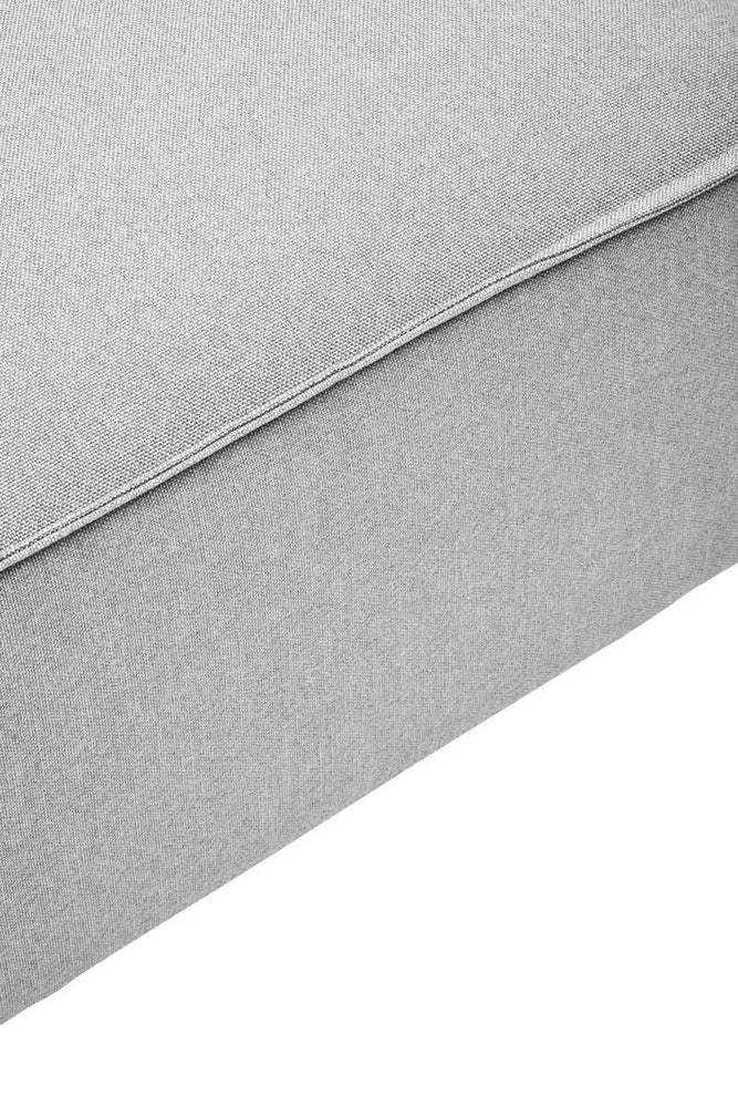 Grey fabric modular ottoman with a smooth texture and clean lines, featuring a simple design and a sturdy base. The ottoman is shown from a close-up angle, highlighting its soft upholstery and subtle stitching details