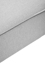 Grey fabric modular ottoman with a smooth texture and clean lines, featuring a simple design and a sturdy base. The ottoman is shown from a close-up angle, highlighting its soft upholstery and subtle stitching details