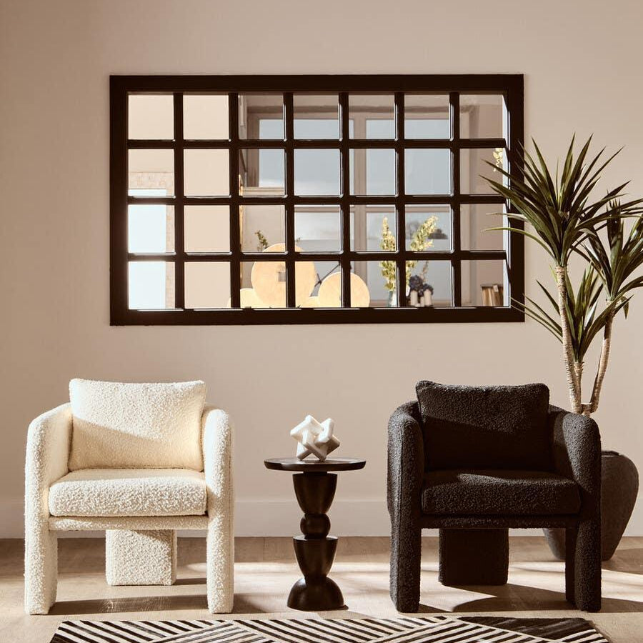 Black and cream boucle armchairs with accent table and geometric rug in modern living room