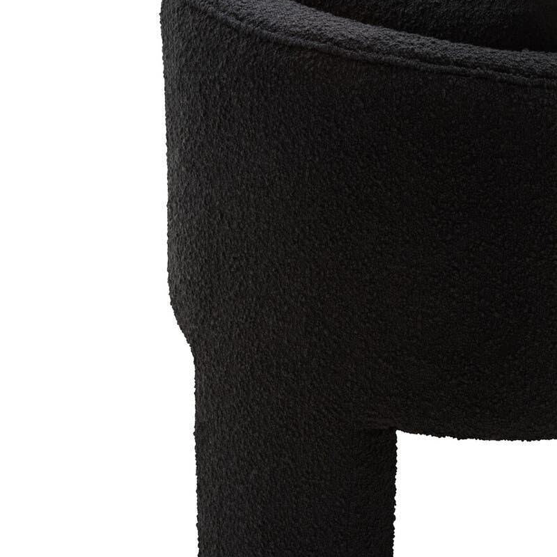 Curved black boucle accent chair with textured upholstery, close-up of arm and backrest