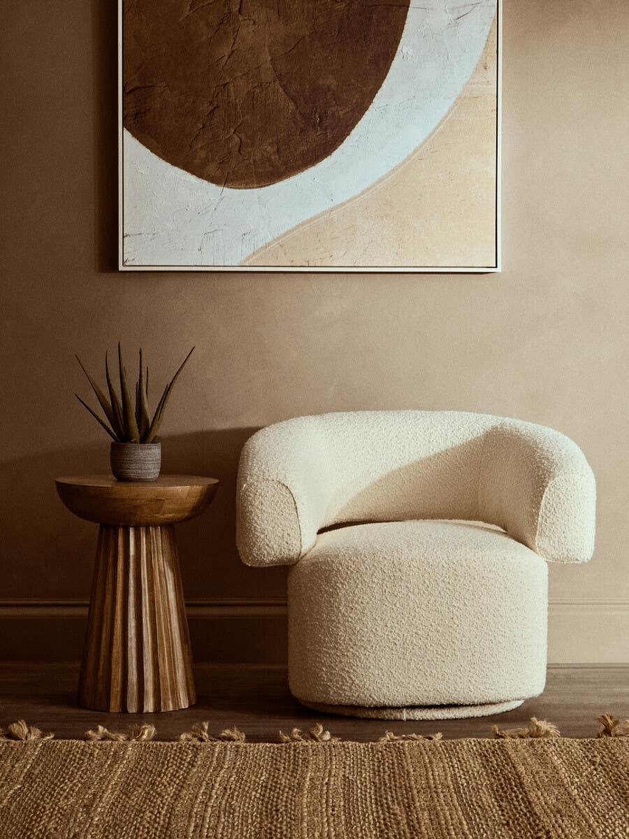 Cream boucle accent chair with curved back next to wooden side table in neutral living room