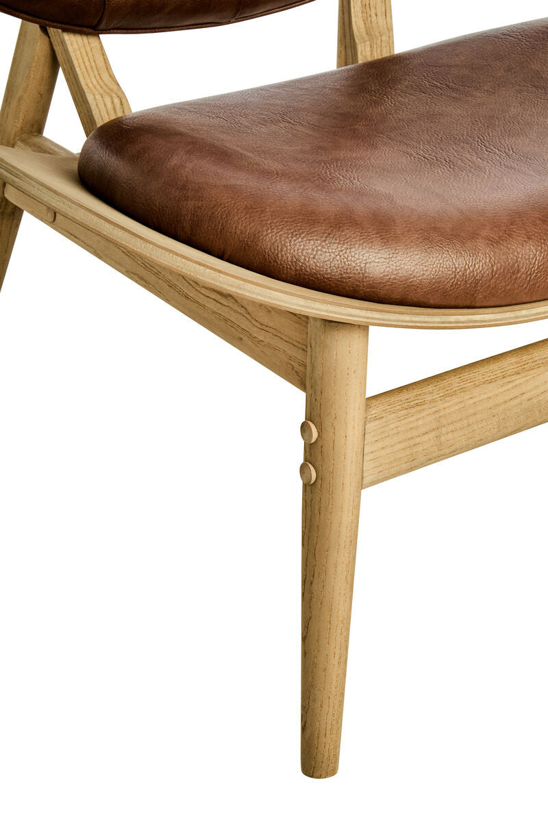 Brown leather effect chair featuring a plush seat and backrest, supported by a light elm wood frame with tapered legs.