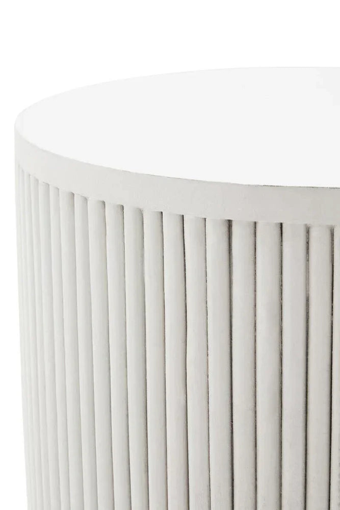 Round ribbed white side table with vertical grooves, close-up of concrete finish