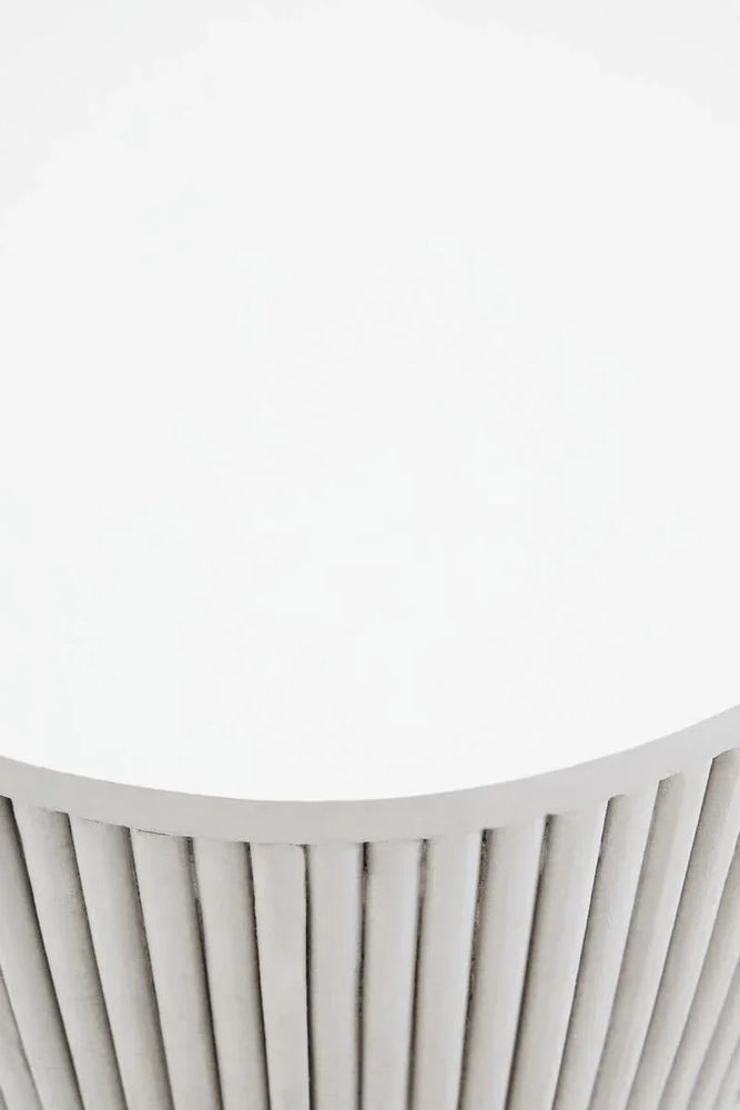 Round white coffee table with vertical slat details on the base, close view