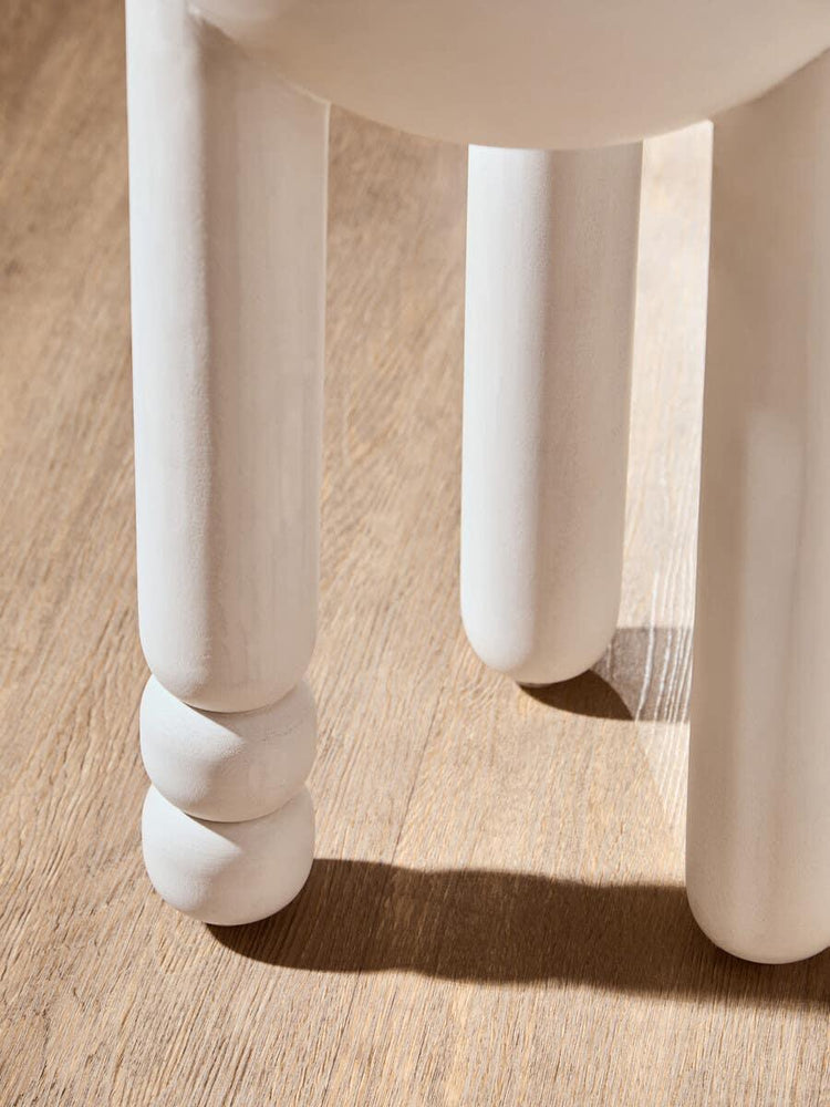 White wooden stool legs on light oak floor, close-up showing rounded detail
