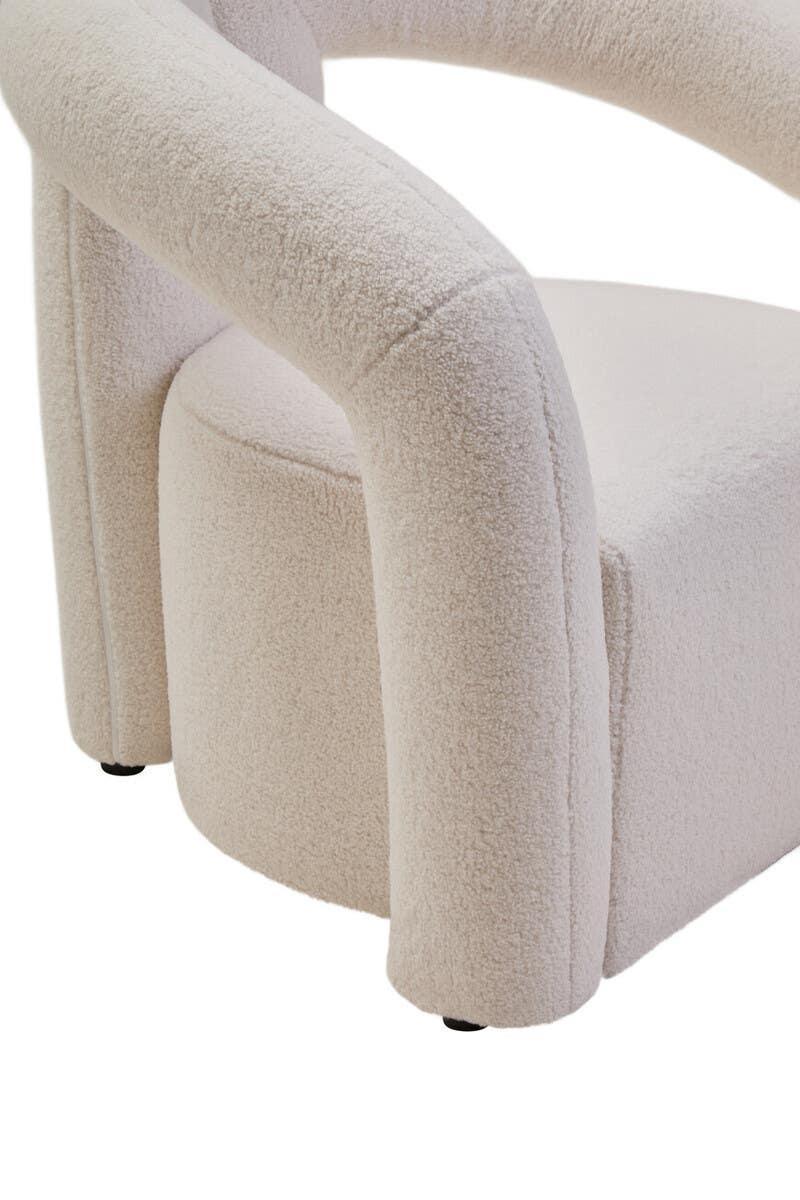 Close-up of cream boucle armchair with curved upholstered arm and rounded seat