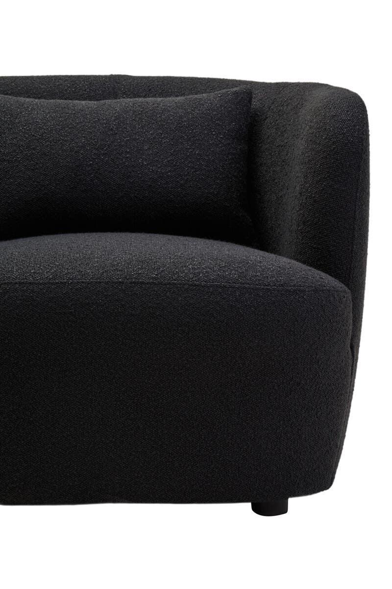 Curved black fabric sofa corner with cushion and rounded armrest
