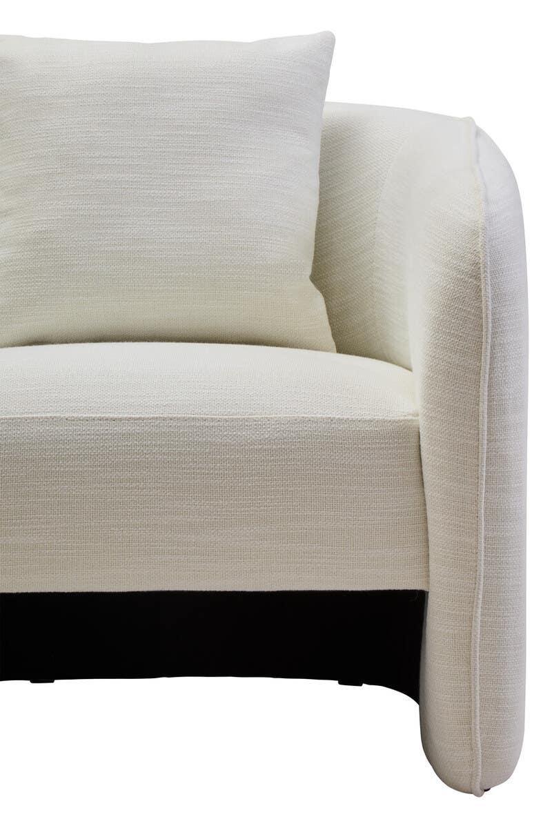 Closeup of cream fabric sofa with rounded armrest and matching cushion