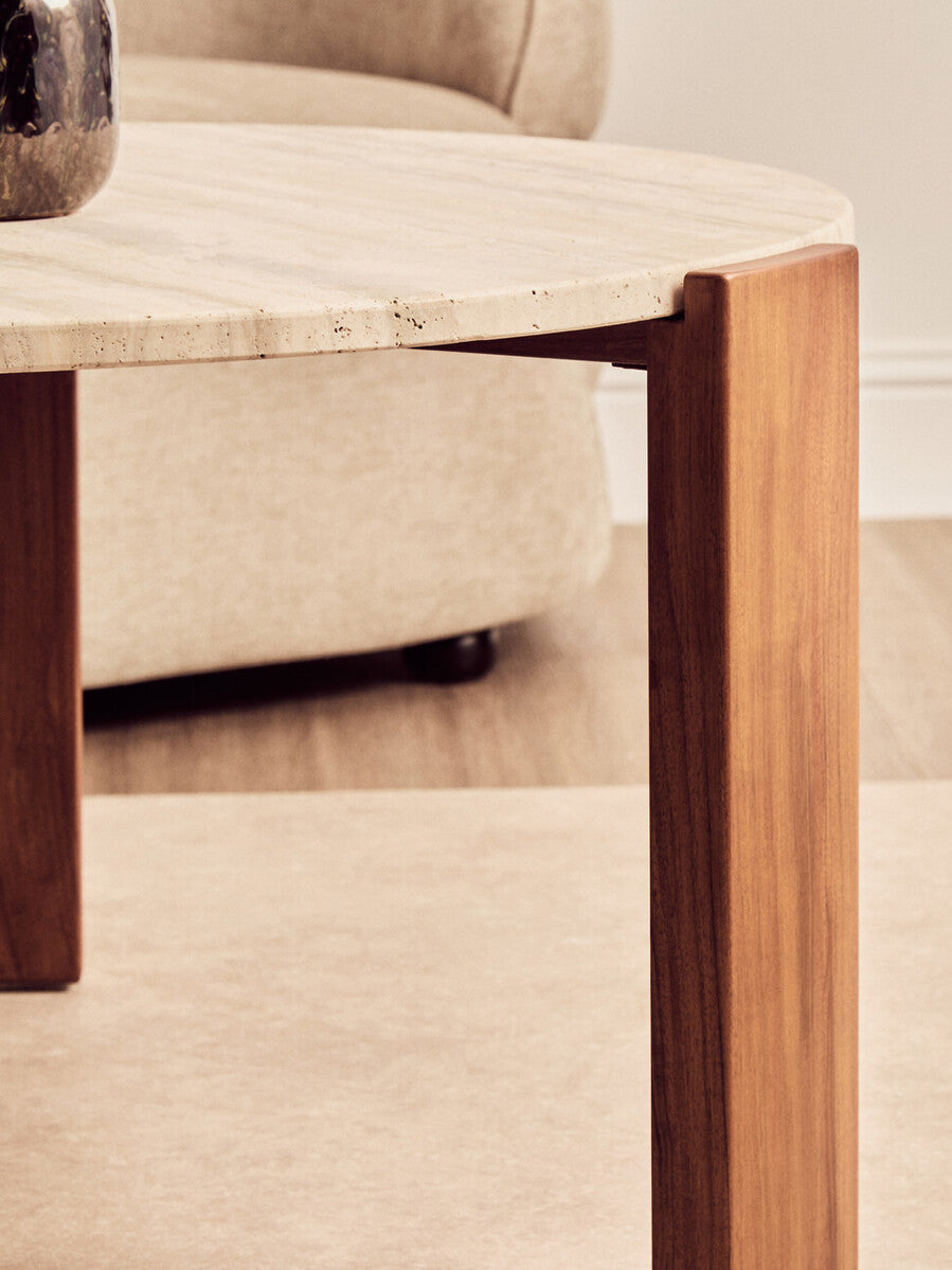 Round coffee table featuring a natural travertine marble top with subtle texture and a smooth edge.