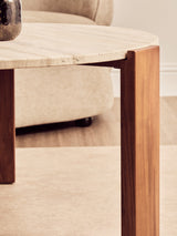 Round coffee table featuring a natural travertine marble top with subtle texture and a smooth edge.