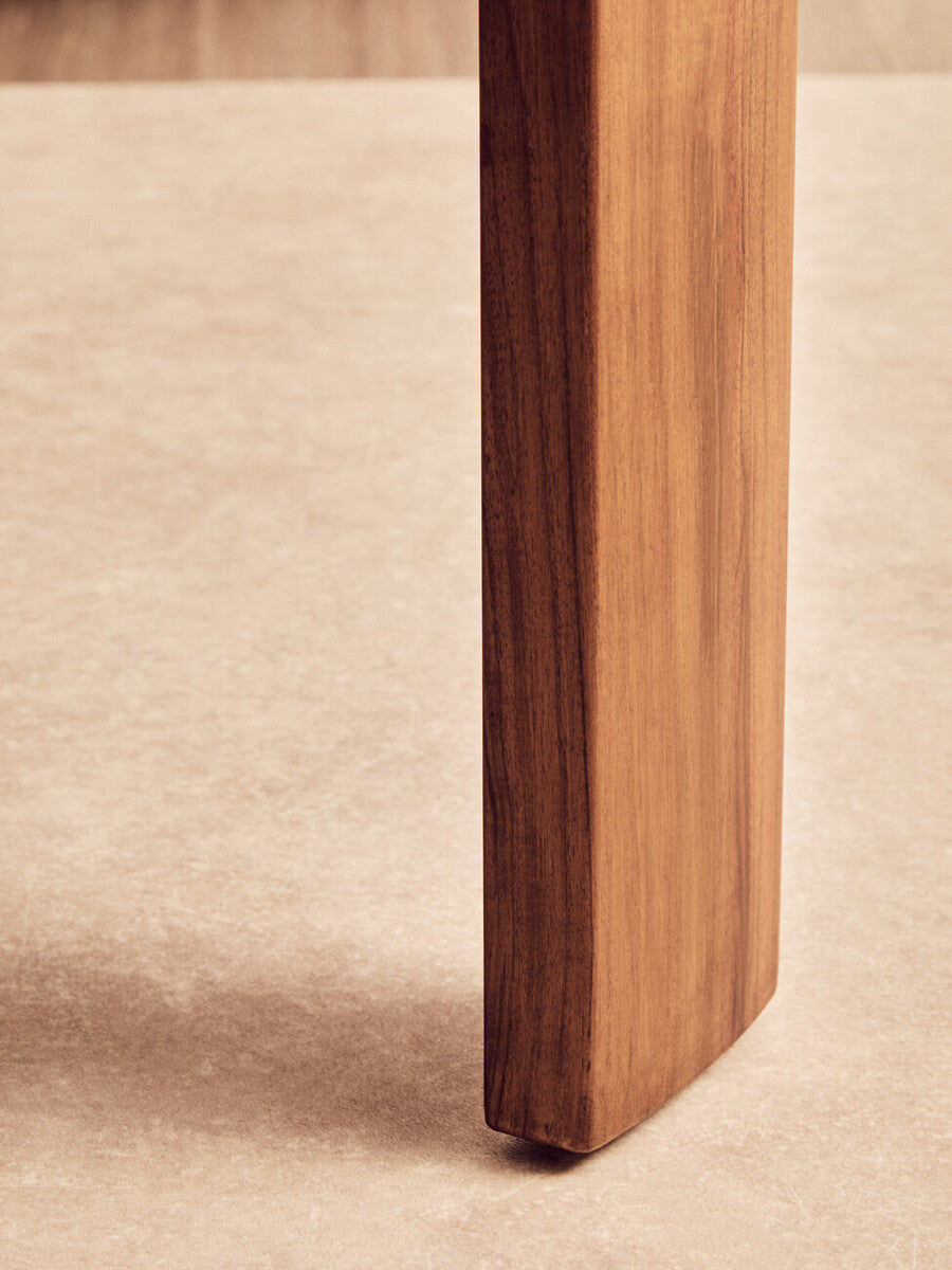 Close-up view of a sturdy acacia wood leg of a round coffee table, showcasing its natural finish and smooth texture, set against a light travertine marble surface.