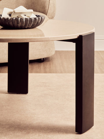 Round cream marble top coffee table featuring sleek black acacia wood legs.