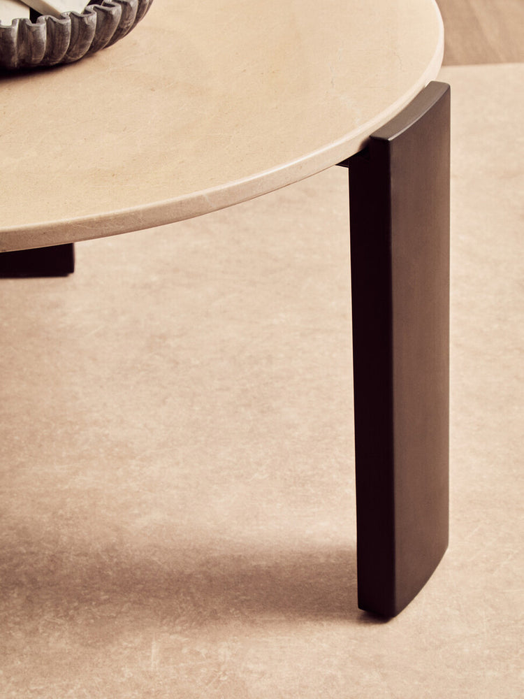 Round cream marble top coffee table featuring a smooth surface and sleek, dark acacia wood legs.