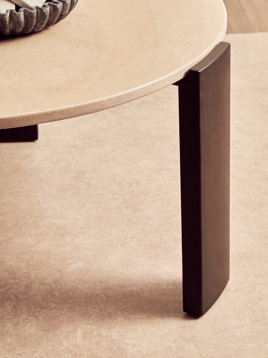 Round cream marble top coffee table featuring a smooth surface and sleek, dark acacia wood legs.