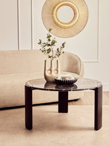 Round coffee table featuring a black and gold marble top with a sleek design, supported by sturdy black acacia wood legs.