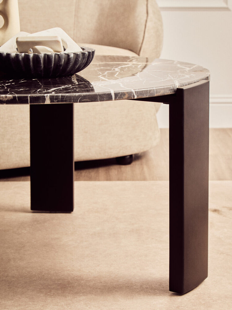 Round coffee table featuring a sleek black marble top with striking white veining, supported by sturdy black acacia wood legs.