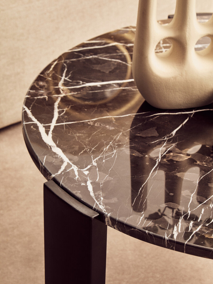 Round coffee table featuring a black marble top with striking white veining, complemented by sleek black wooden legs.