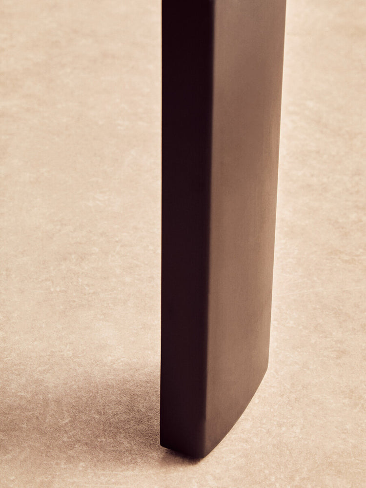 Close-up view of the leg of a round coffee table featuring a sleek black finish, showcasing a smooth, modern design.