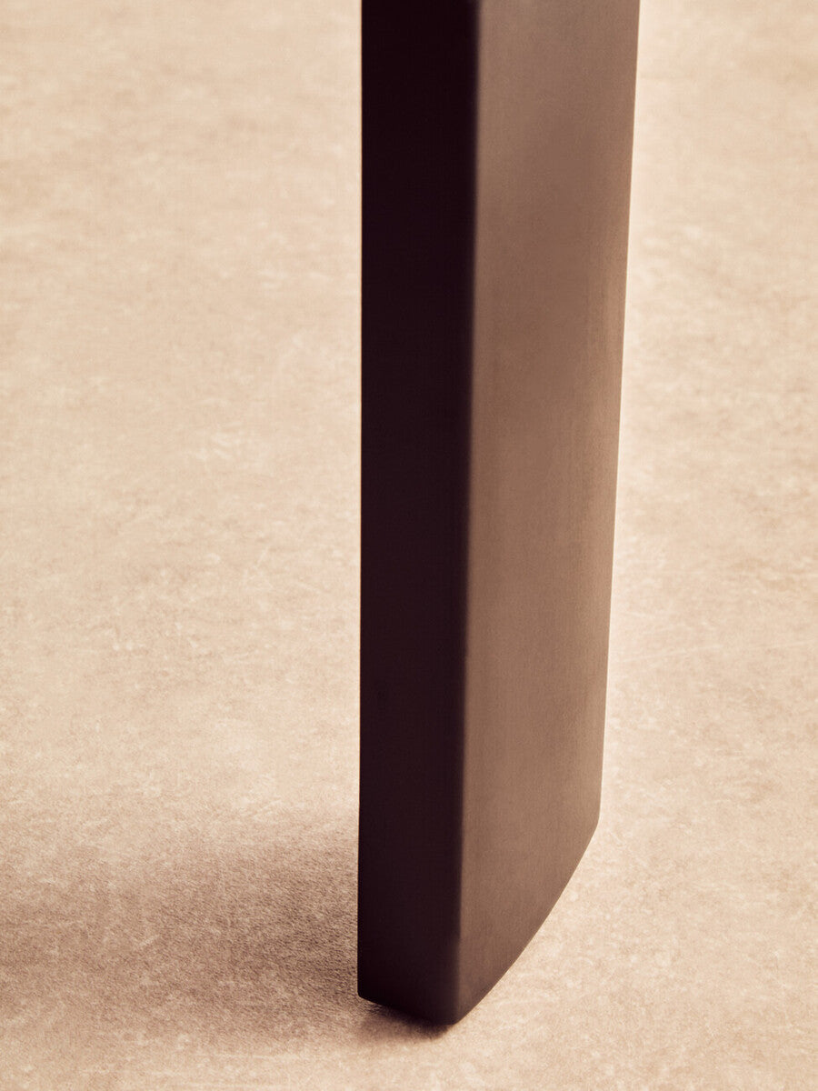 Close-up view of the leg of a round coffee table featuring a sleek black finish, showcasing a smooth, modern design.