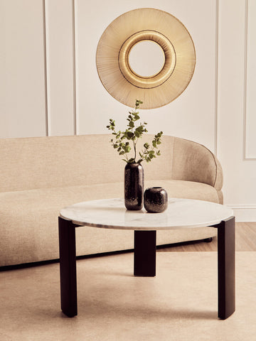 Round coffee table featuring a smooth white marble top with subtle gray veining, supported by four sleek black acacia wood legs.
