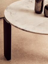 Round coffee table featuring a white marble top with subtle gray veining, supported by sleek black acacia wood legs.