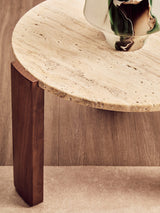 Round coffee table featuring a cream travertine marble top with natural textures and patterns, supported by two sturdy acacia wood legs.