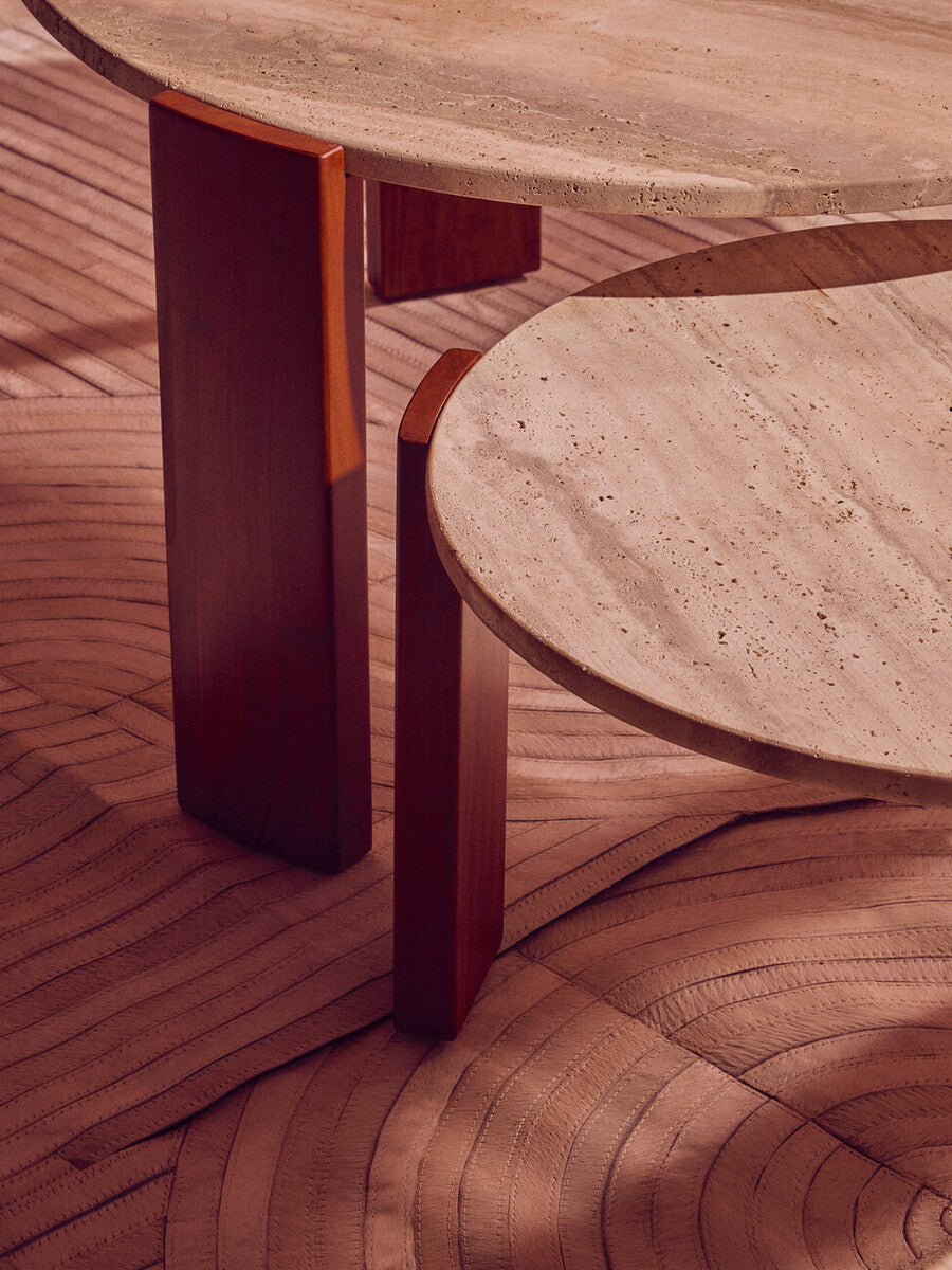 Round coffee table featuring a cream travertine marble top with a smooth, textured surface, supported by two sturdy acacia wood legs in a rich brown finish.