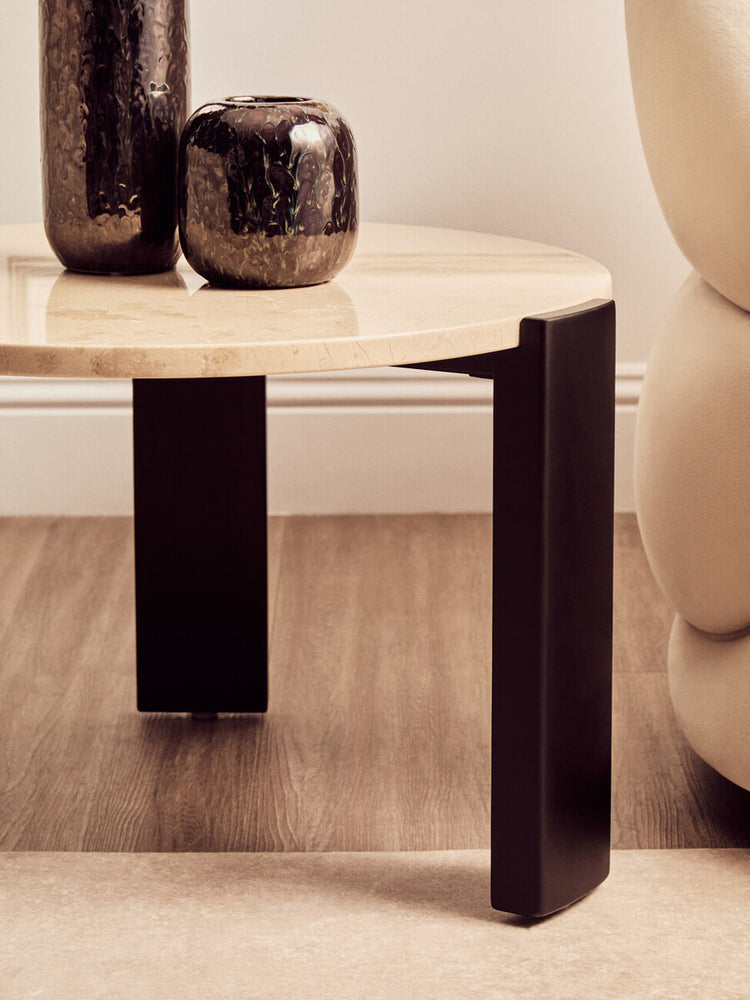 Round cream marble top coffee table featuring sleek black acacia wood legs.