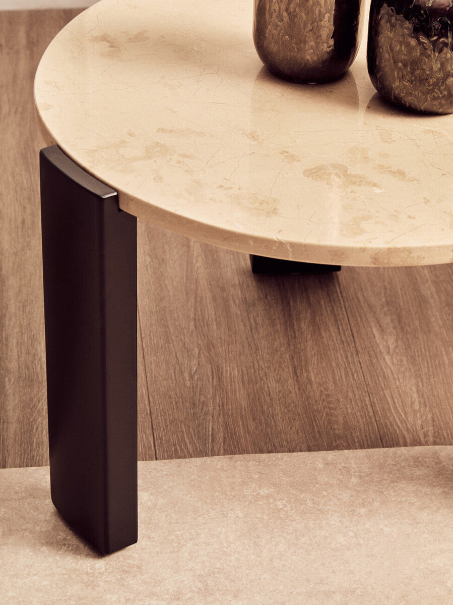 Round cream marble top coffee table featuring a smooth surface with subtle veining, supported by sleek black acacia wood legs.