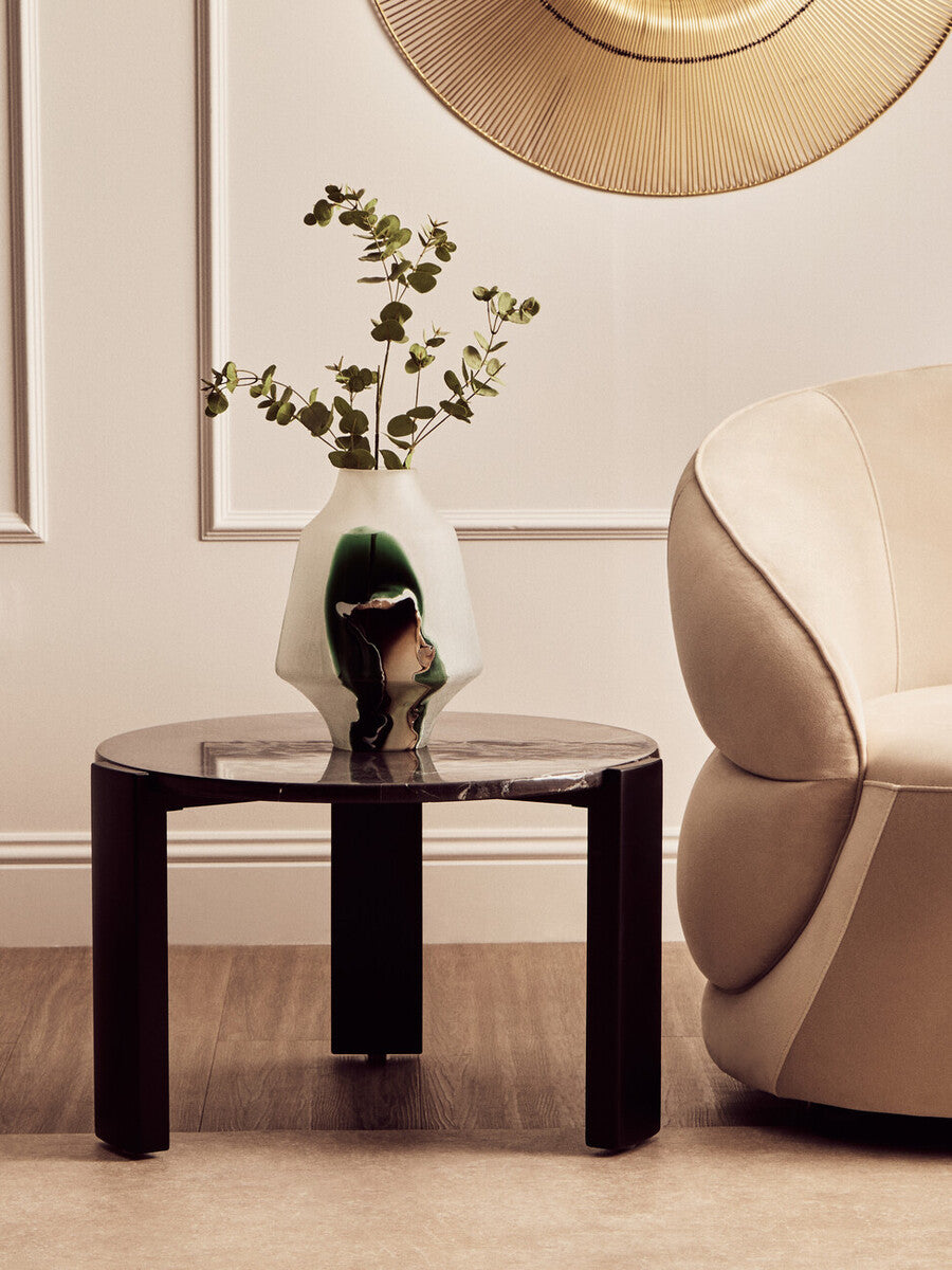 Round black marble top coffee table with a sleek acacia wood base, featuring a minimalist design.