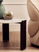 Round white marble top coffee table featuring a sleek black acacia wood base.