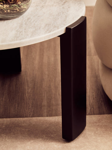 Round coffee table featuring a white marble top with subtle veining, supported by sleek black acacia wood legs.