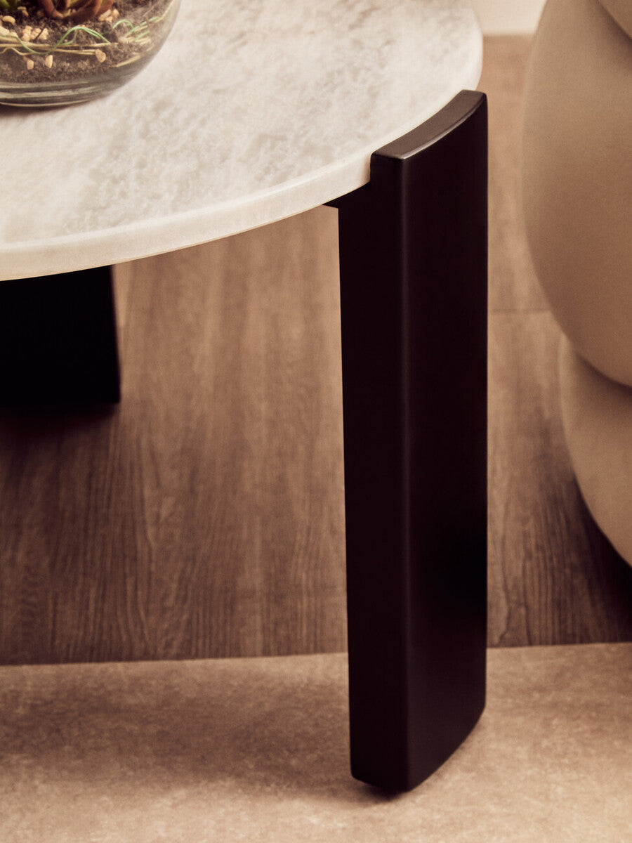 Round coffee table featuring a white marble top with subtle veining, supported by sleek black acacia wood legs.