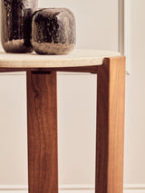 Round side table featuring a smooth travertine top with a natural stone finish, supported by sturdy acacia wood legs in a rich brown hue.