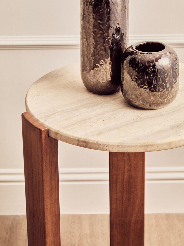 Round side table featuring a smooth travertine top with a natural beige finish, supported by sturdy acacia wood legs in a rich brown hue.