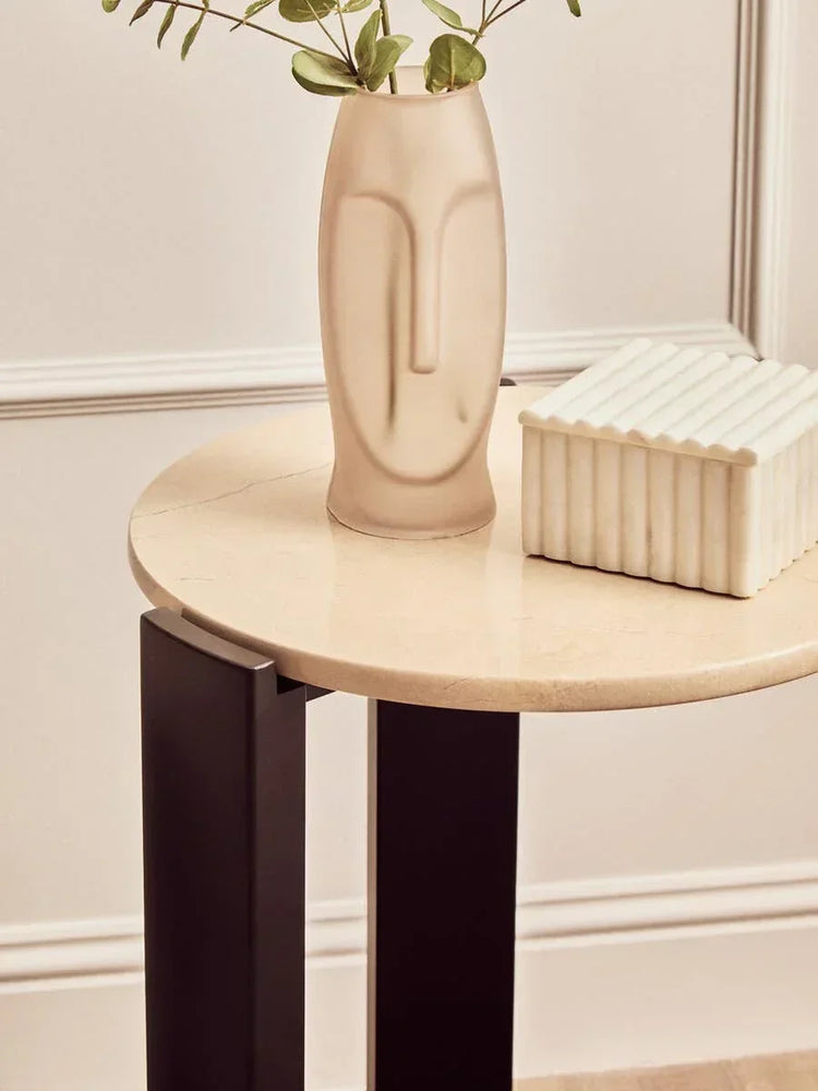 round marble side table with black legs styled with ceramic vase and decorative box