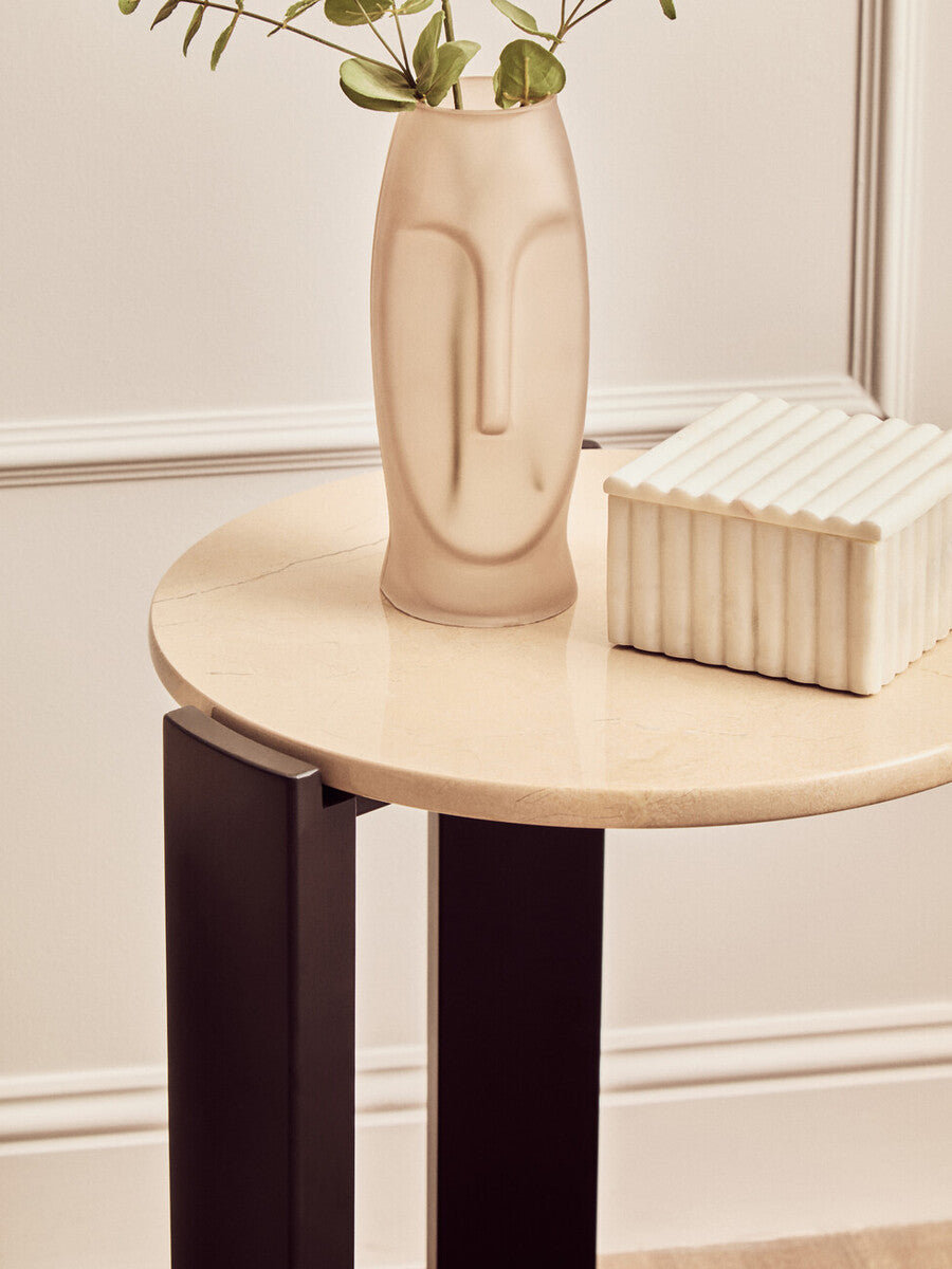 Round side table featuring a cream marble top with subtle veining, supported by sleek black acacia wood legs.