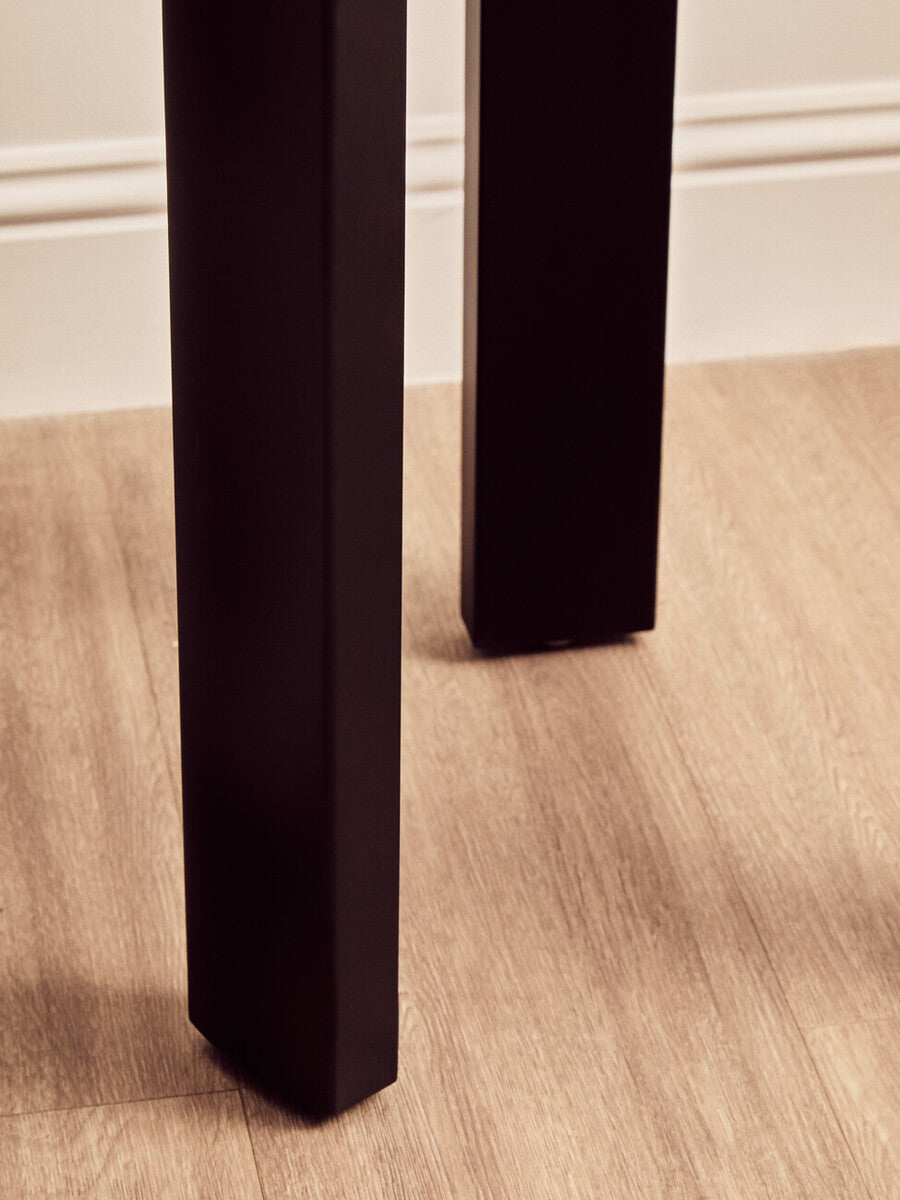 Close-up view of the sturdy black acacia wood legs of a round side table, showcasing their clean lines and modern design.