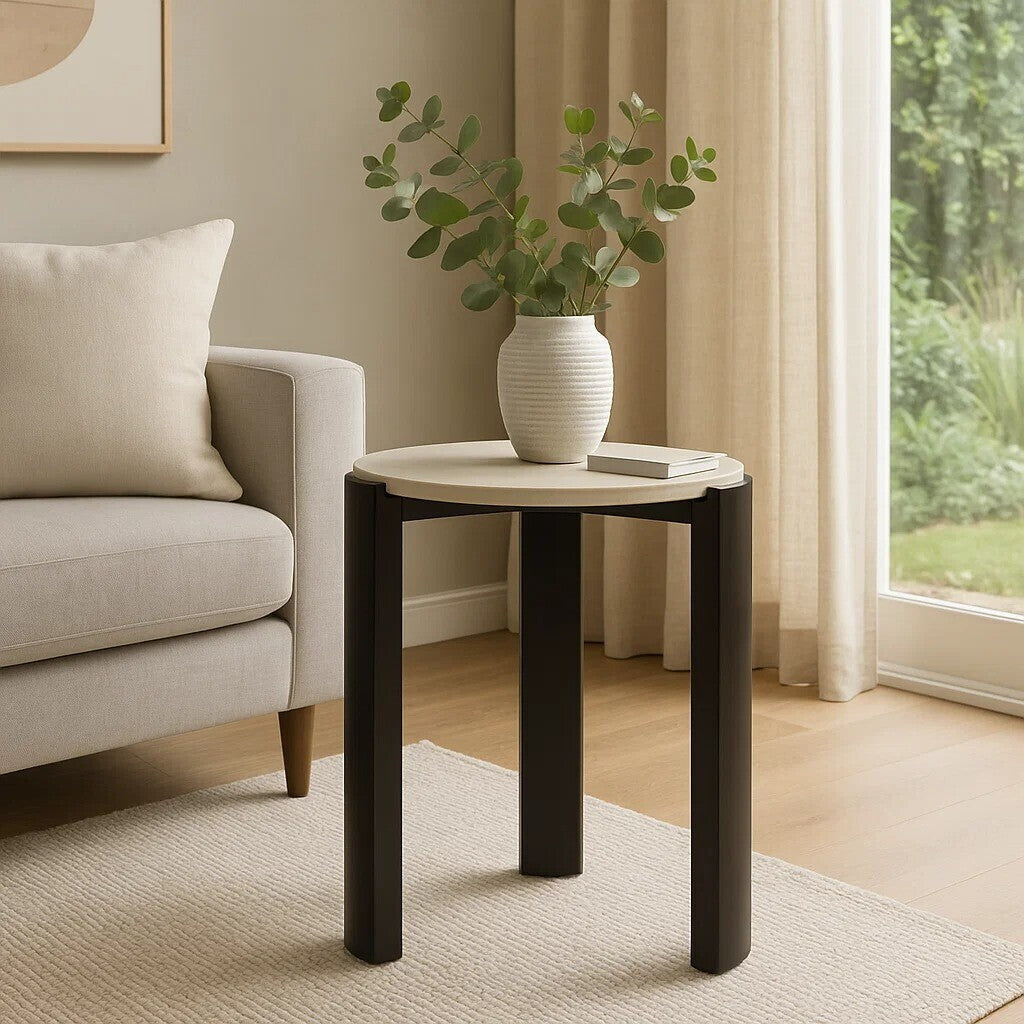 Round side table featuring a cream marble top and sleek black acacia wood legs.