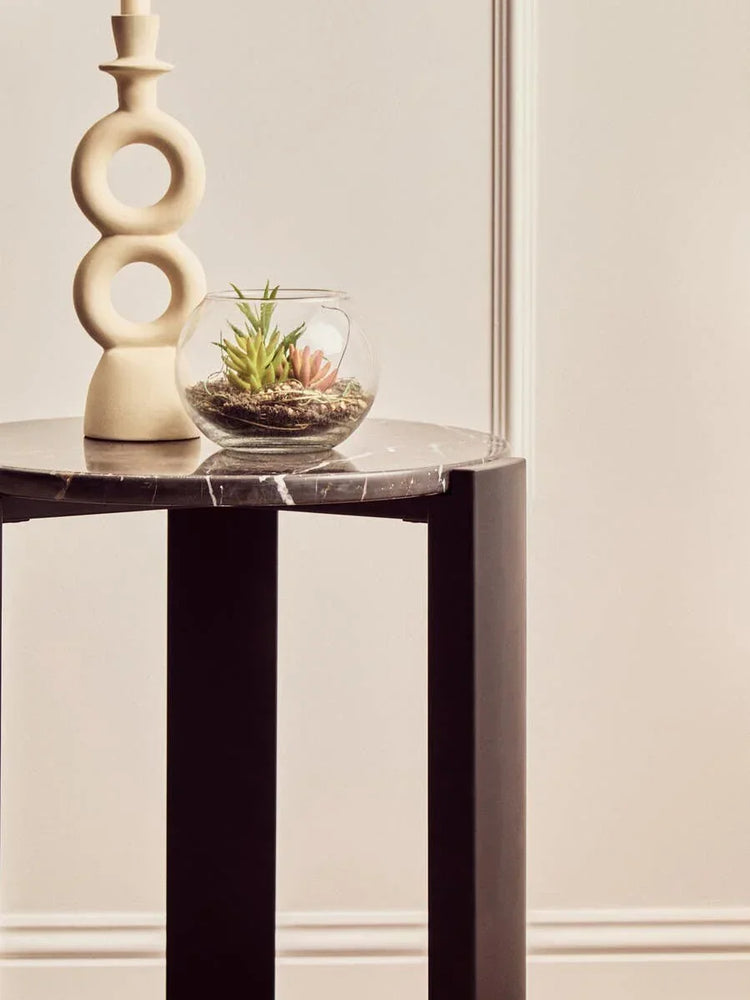 Black marble side table with decorative vase and glass terrarium with succulents