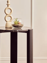 Round side table featuring a black and gold marble top, supported by sleek black acacia wood legs.