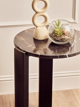 Round side table featuring a black and gold marble top with a glossy finish, supported by sleek black acacia wood legs.
