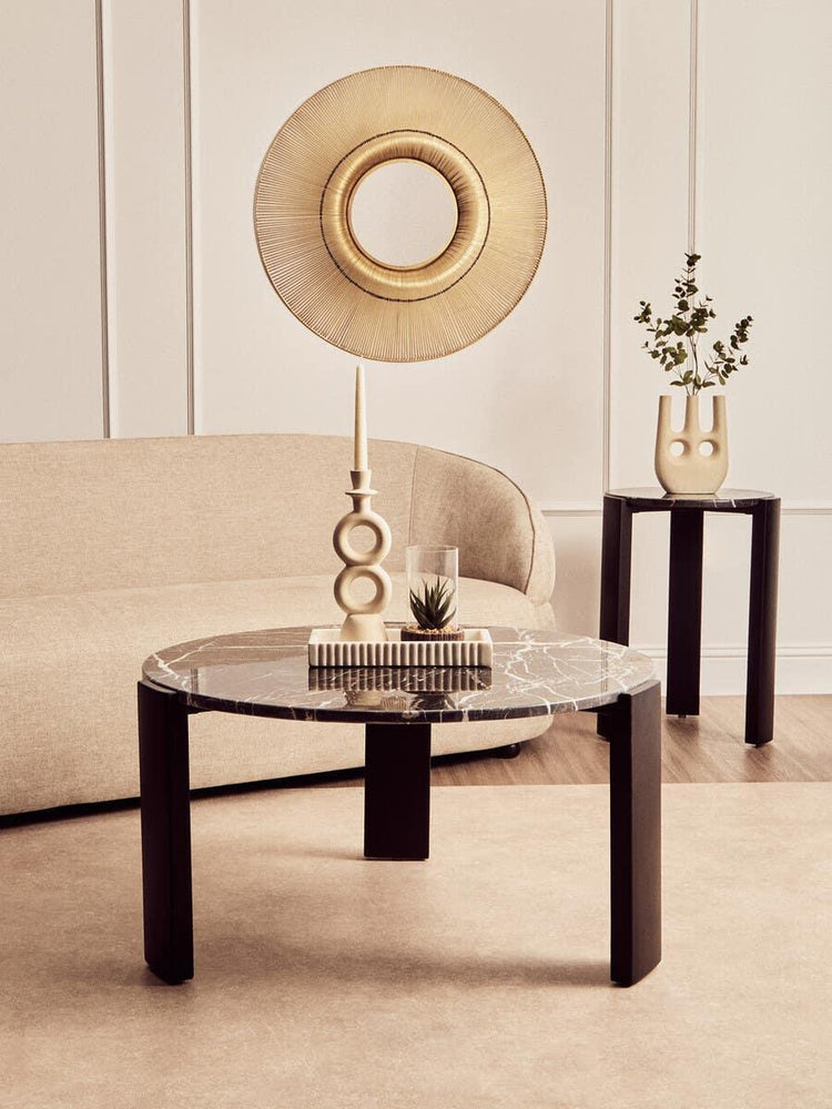 Black marble coffee table with decorative objects in modern living room setting