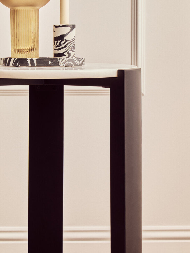Round side table featuring a sleek white marble top and sturdy black acacia wood legs.