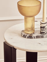 Round side table featuring a smooth white marble top with subtle veining, supported by sleek black acacia wood legs.