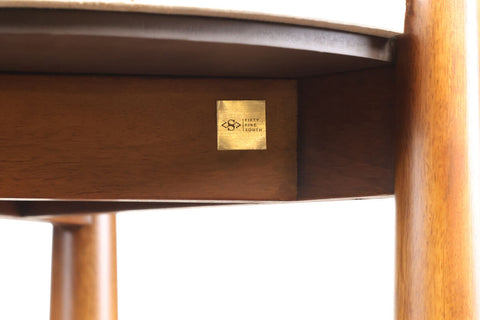 Close-up view of a side table featuring a natural brown finish mango wood base and a smooth travertine top.