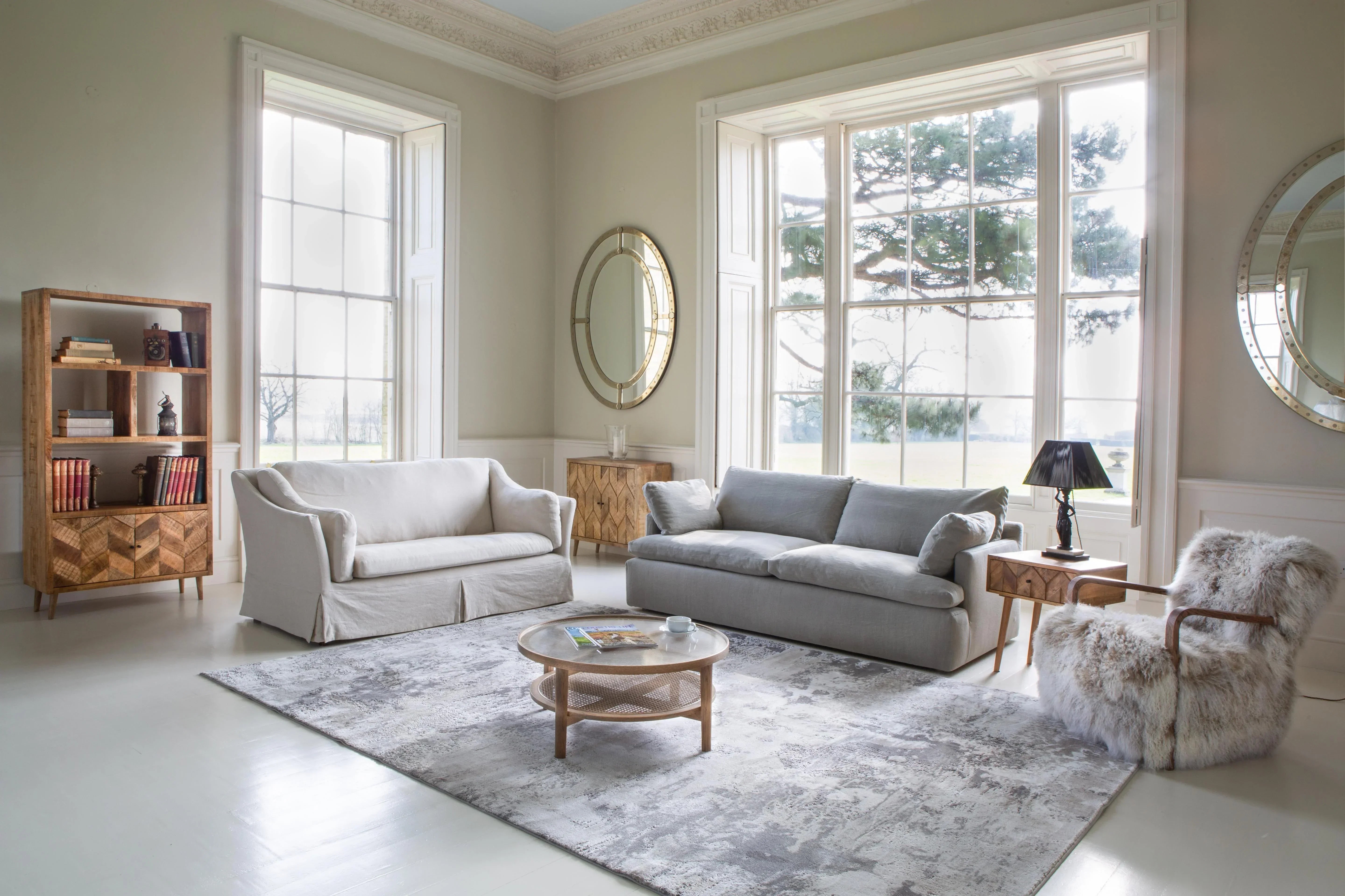 Neutral living room with grey sofa, cream armchair, wooden coffee table and bookcase