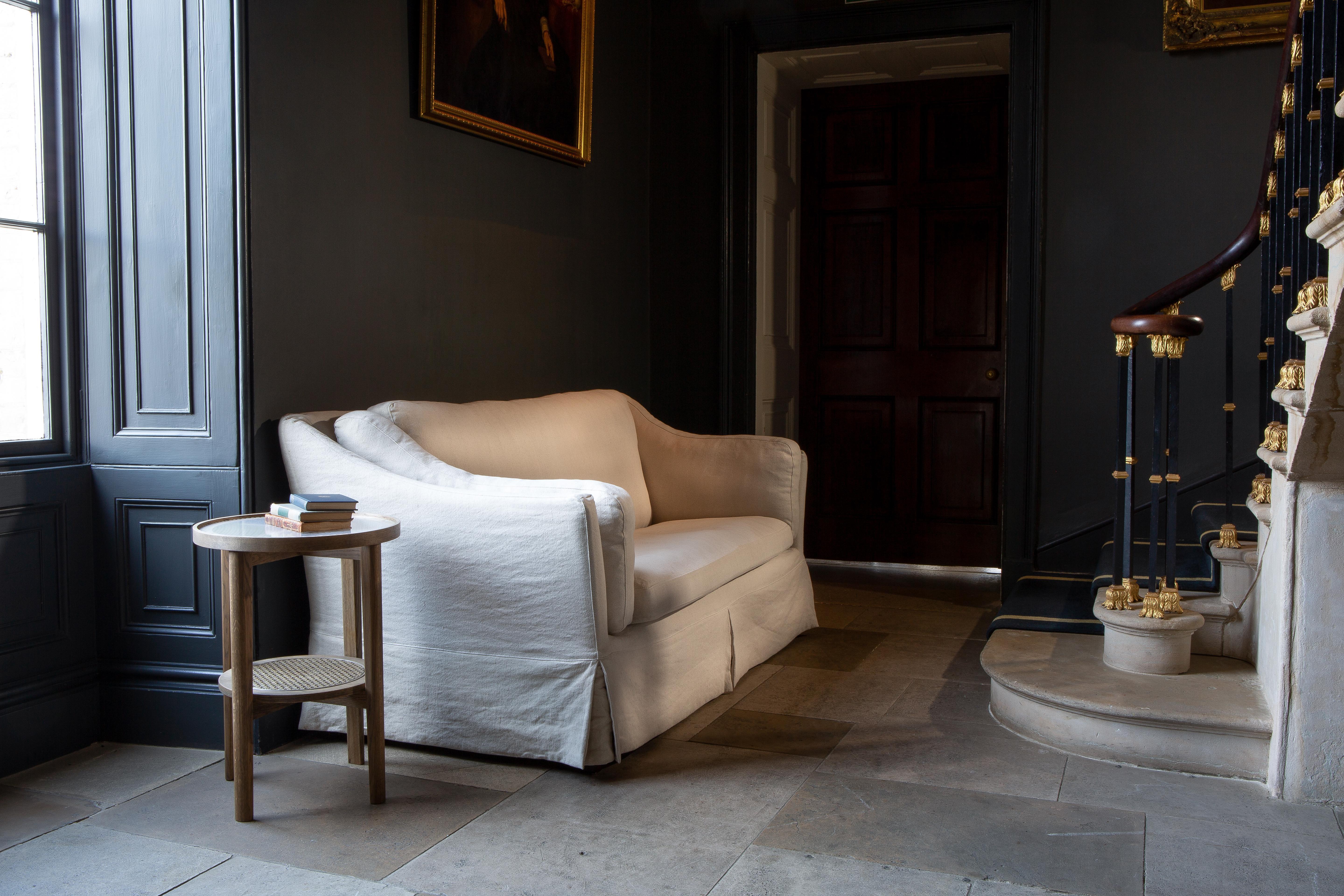 Cream fabric sofa and round wooden side table in hallway beside staircase
